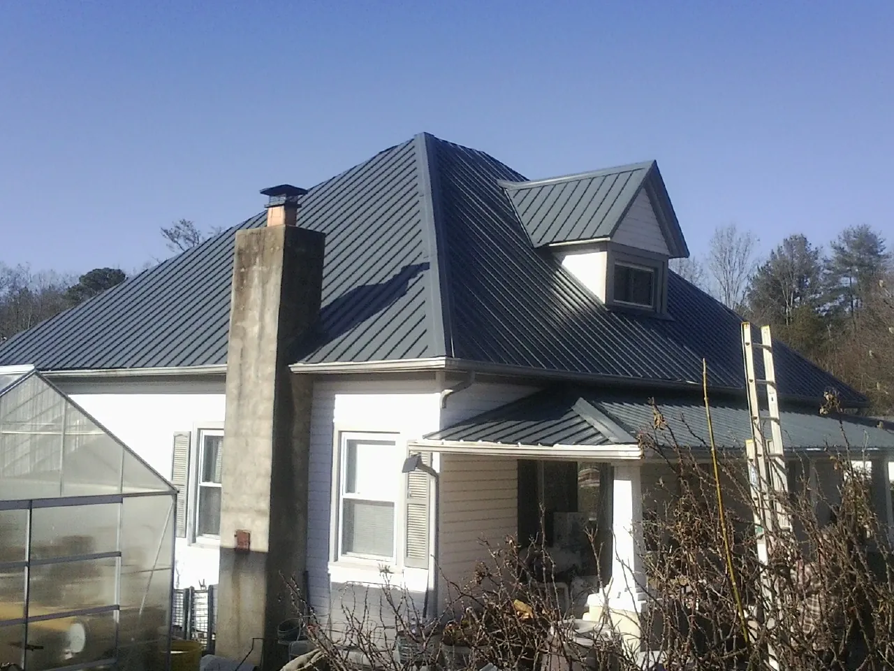 Dark blue standing seam metal roof on a white farmhouse with dormer — Slate & Tile Roof Repair by Roofing Brothers in Allport