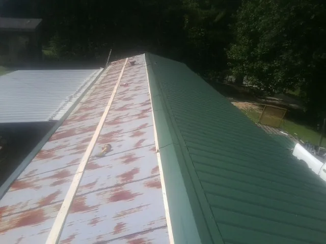 Old rusted panels beside newly installed green metal roofing — Wind Damage Roof Repair by Roofing Brothers in Allport