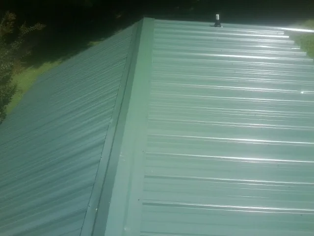 New green metal panels meeting at the ridge of a roof — Flat Roof Repair work by our crew in Allport