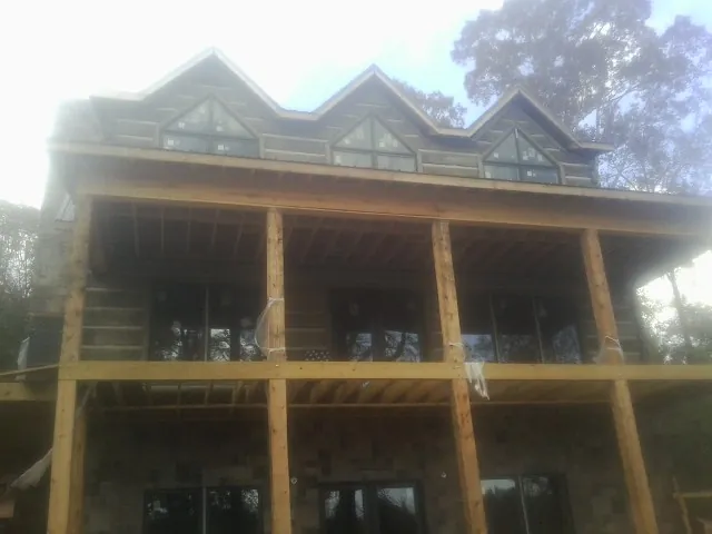 Dormers and porch framing on a large log home under construction — Roof Coating work by our crew in Allport