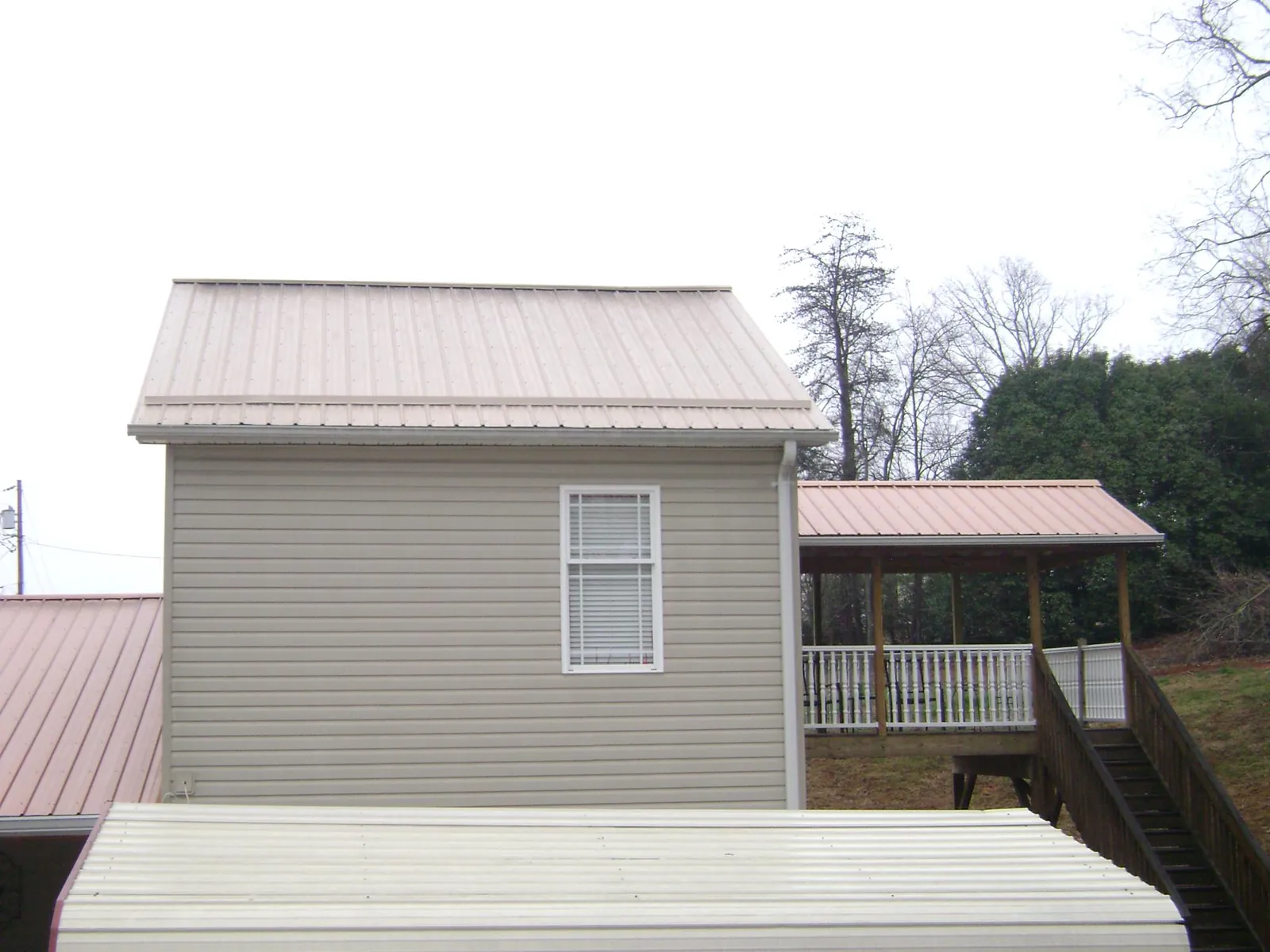 Tan metal roofs on a two story addition and attached porch, from a Roof Replacement job in Allport