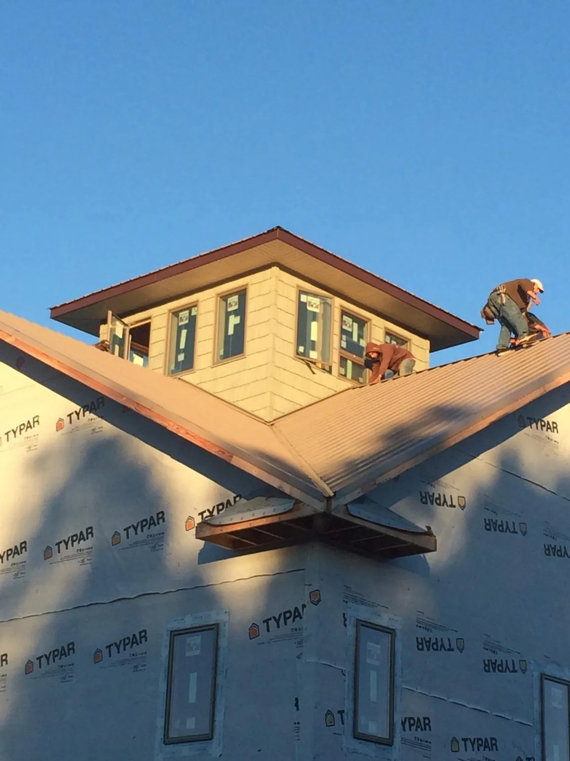 Roofers working around a rooftop cupola on a new metal roof at sunset — Roof Waterproofing in Allport by Roofing Brothers